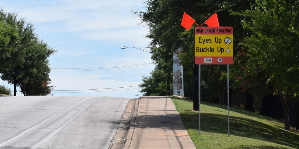 Photo of a sign on Pleasant Valley Road at Oltorf Street that says "High-Crash Roadway. Eyes up, Buckle up"