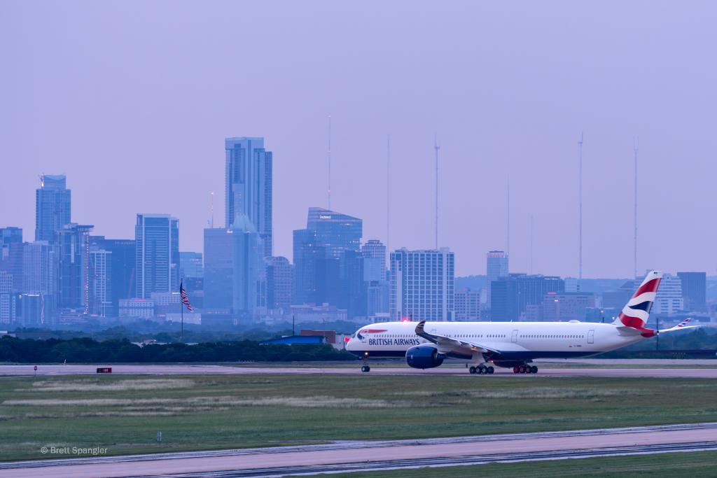 Photo of a British Airways aircraft readying for take-off with Downtown Austin in the background.