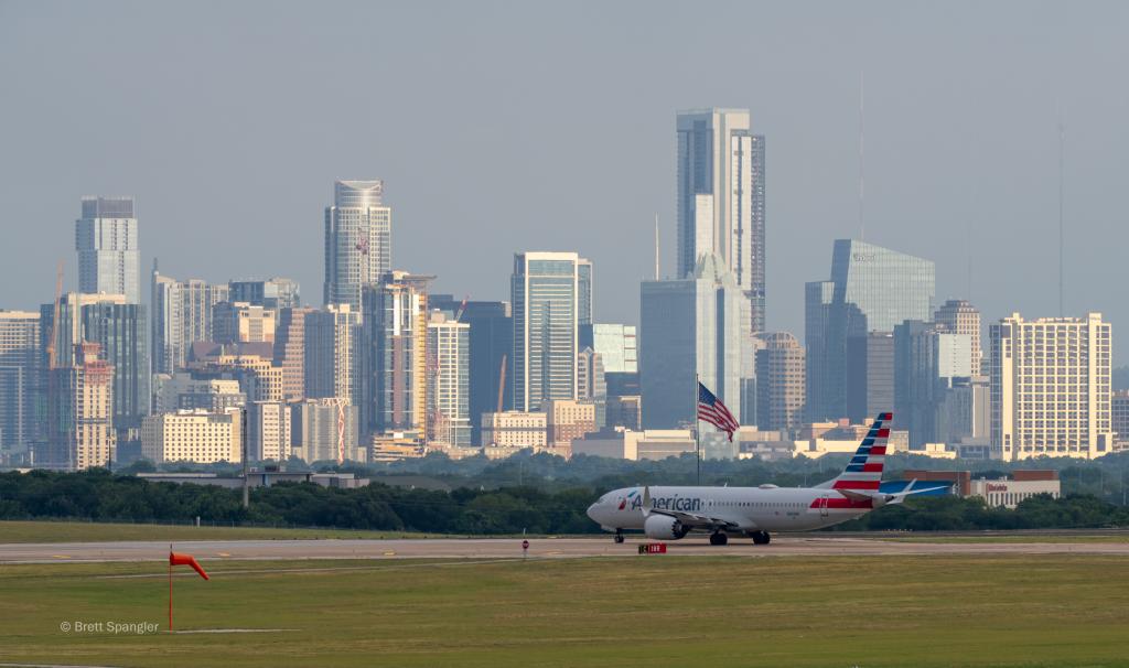 An American Airlines aircraft waiting to take off with DOwntown Austin in the background