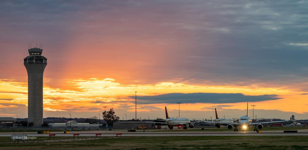 Photo taken from the Family Viewing Area of planes on the airfield at sunset. The ATC tower is to the left.