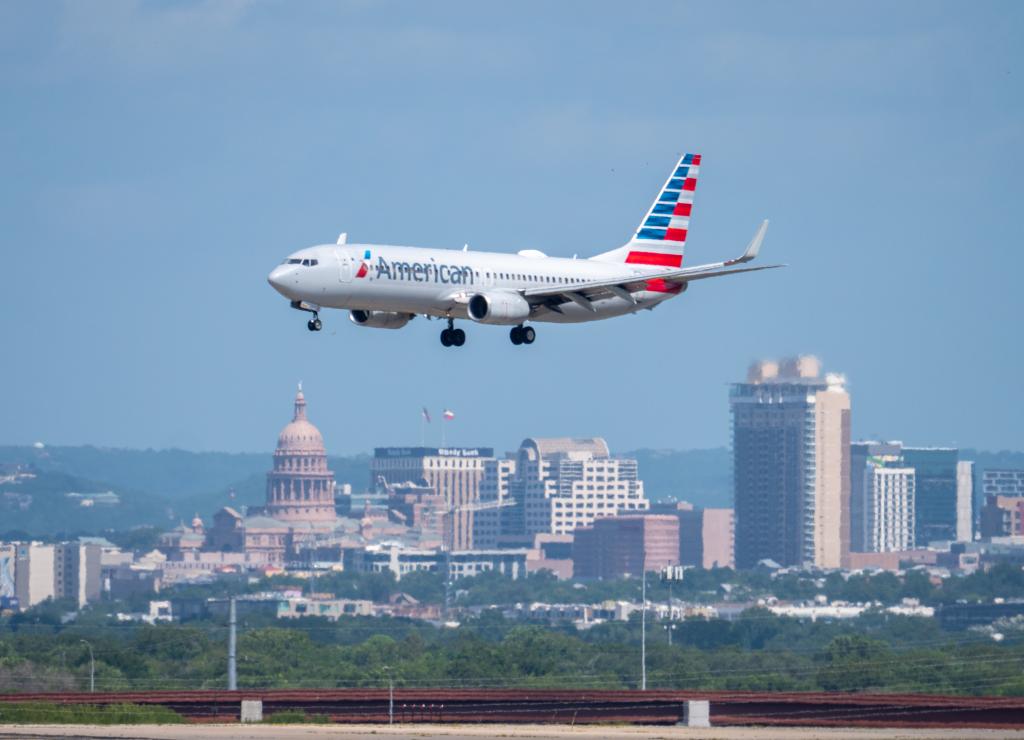 Photo of an American Airlines plane arriving at AUS. Downtown Austin is in the background.