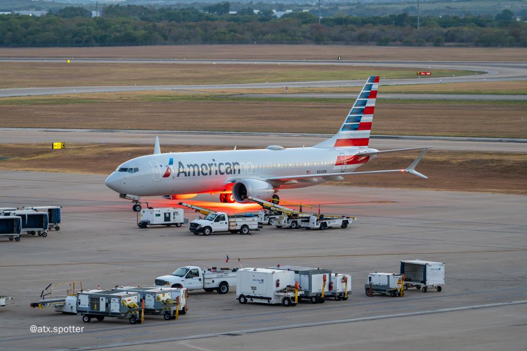 Photo of an American Airlines plane taxiid at AUS. Vibrant colored lights are underneath it.