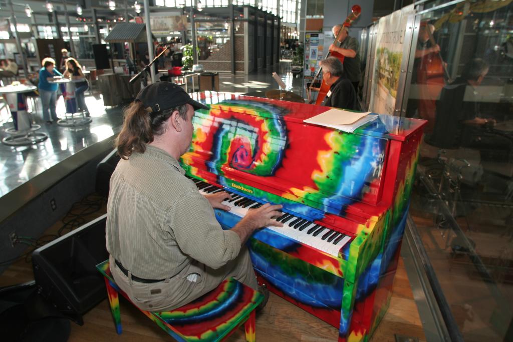 A musician plays AUS's famous tie dye piano on stage.