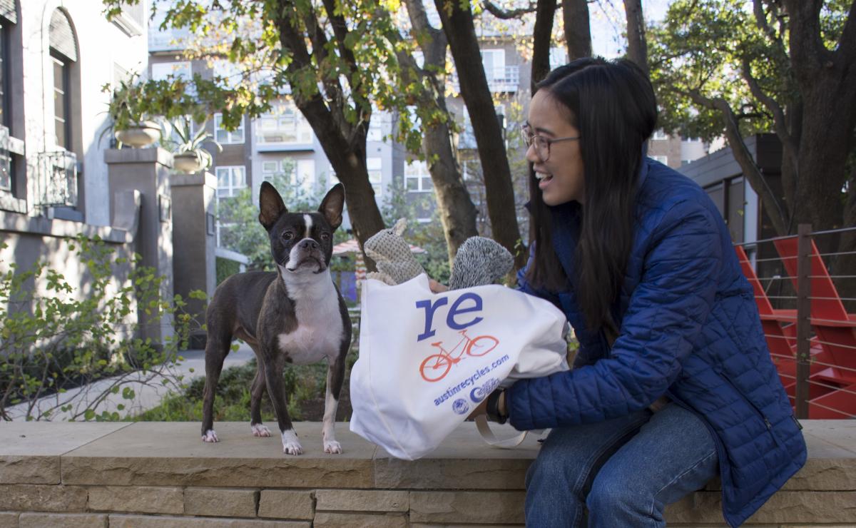 Woman presents a gift to her Boston Terrier in a reusable bag