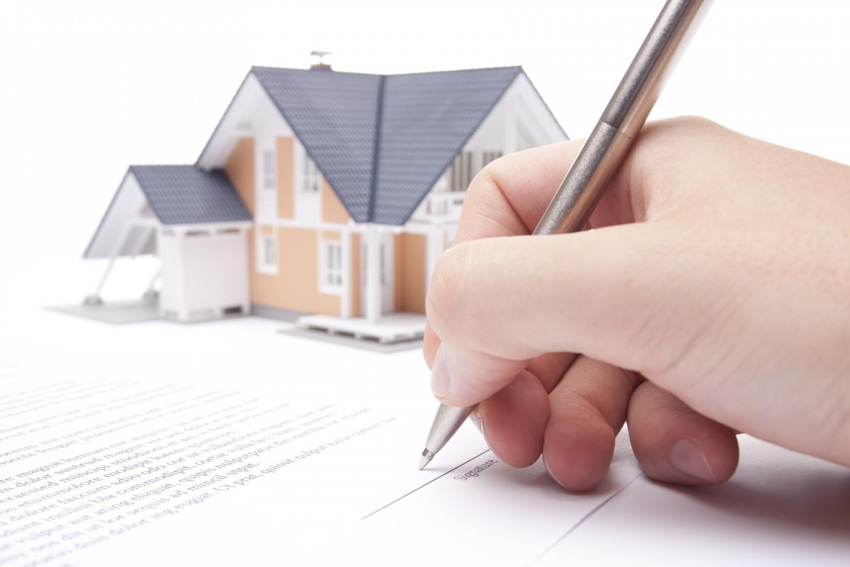 Picture ofhand signing next to a home