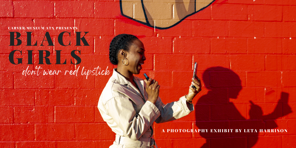 Woman applying lipstick against red wall