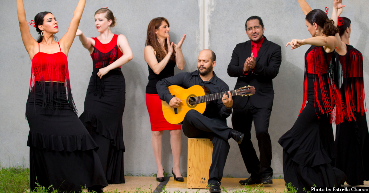 Flamenco dancers dancing around a man seated playing the guitar. Photo credit reads "Photo by Estrella Chacon"