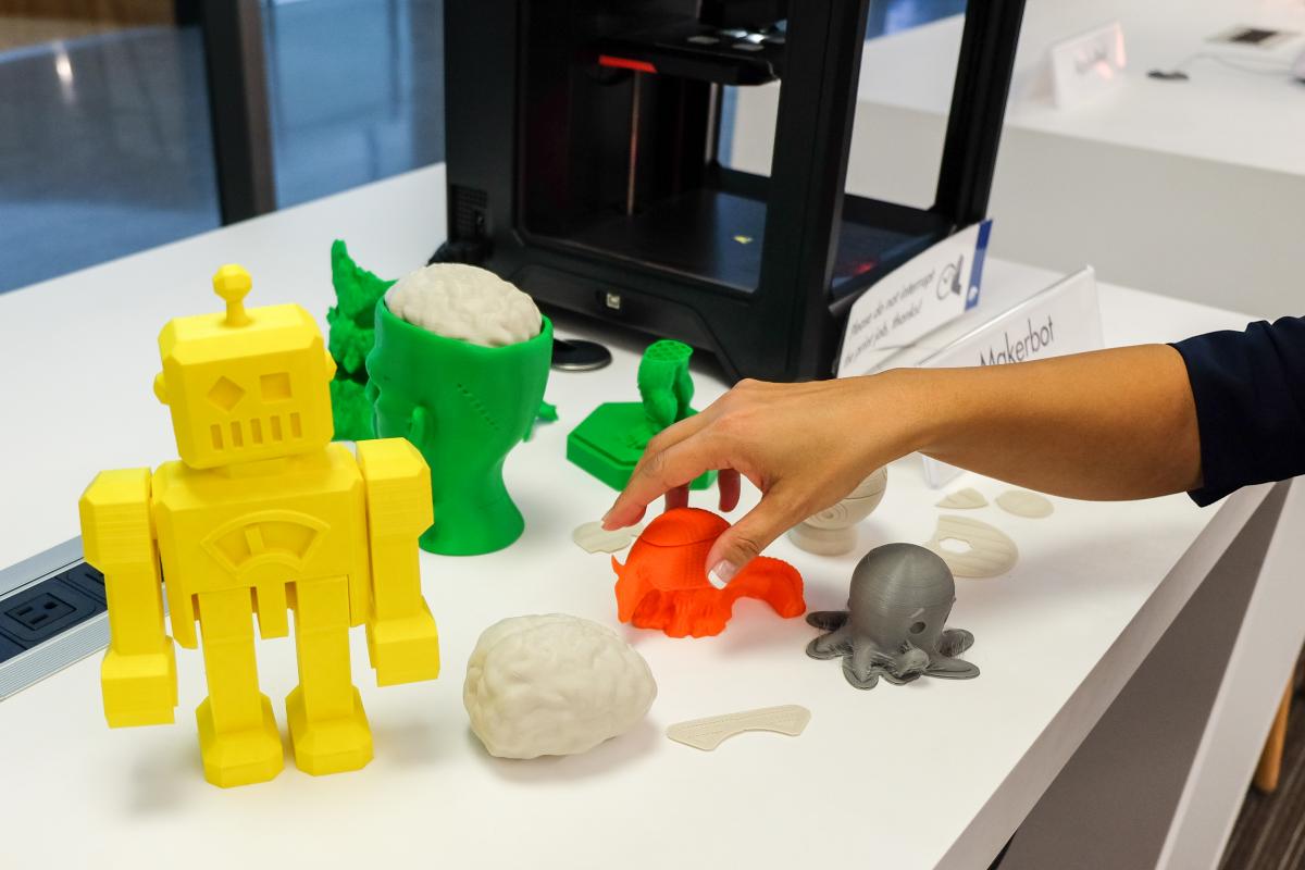 Close up of 3d printer creations, including a yellow robot, green head with a brain, orange armadillo, and grey octopus.