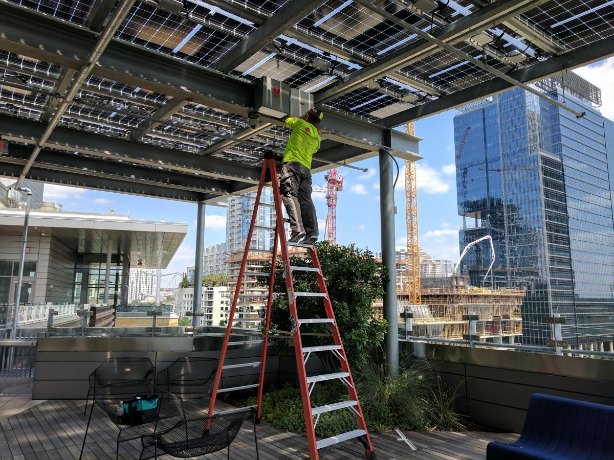 Worker on ladder working on solar panels