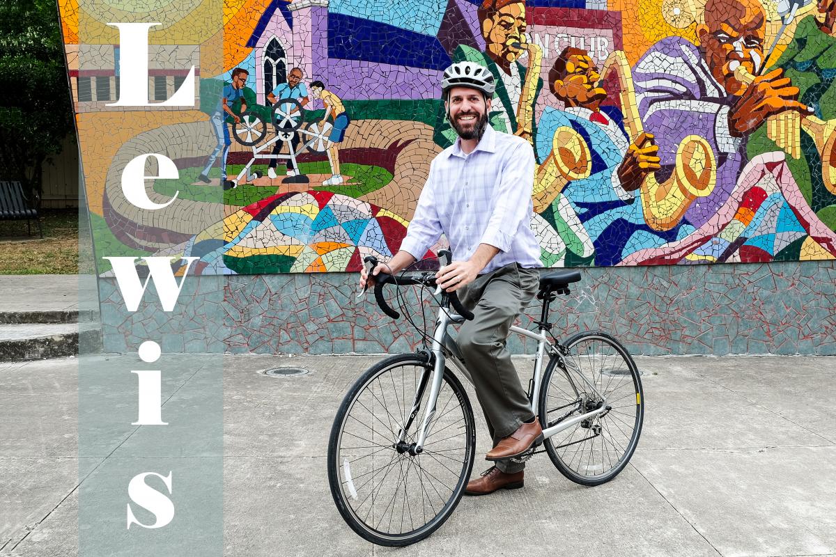 Text: Lewis, picture of Lewis on a bike with colorful mural in background