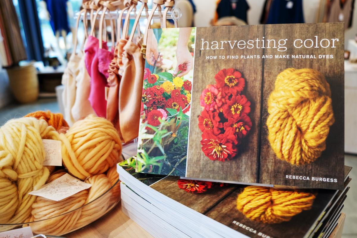 Book titled "Harvesting color" with colorful bags and yarn.
