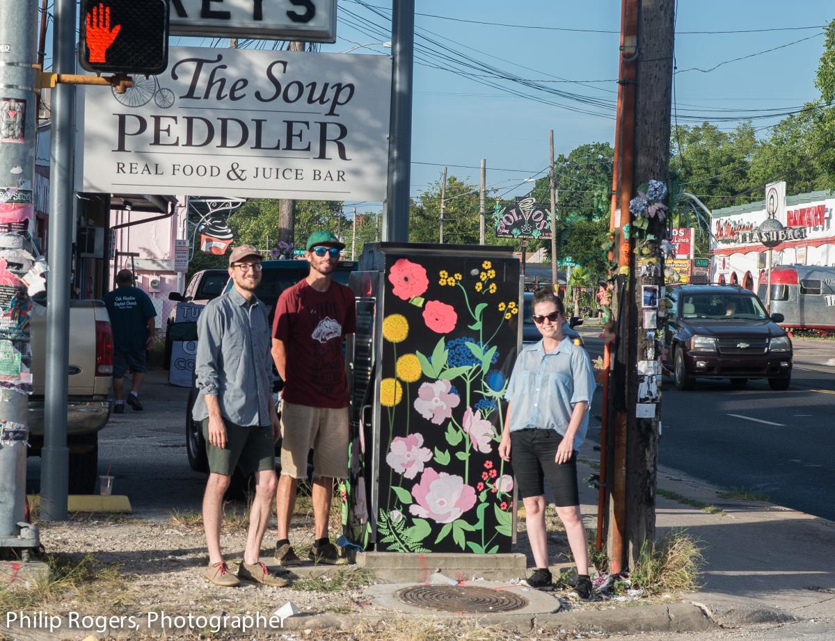 Volunteers standing in front of a designed artbox painted with flowers.
