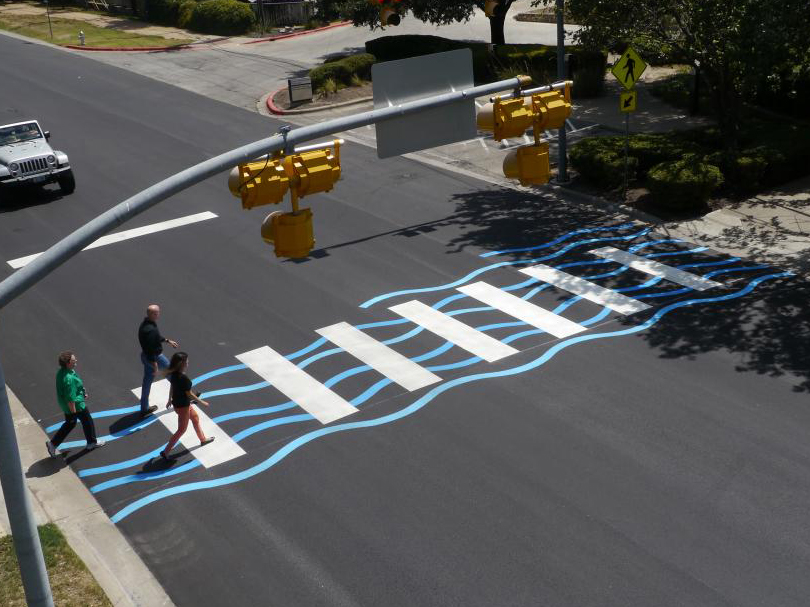 A creative crosswalk with a blue ripple paint design on Lake Austin Boulevard.