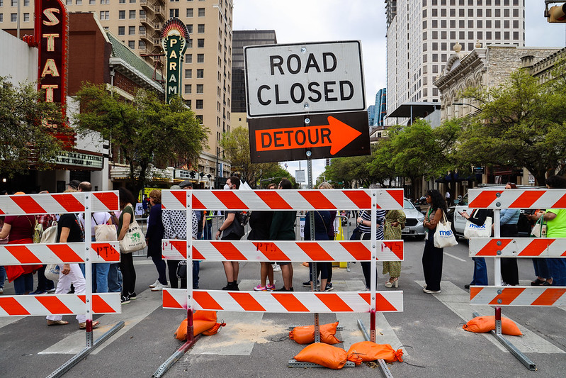 A picture of a downtown street in Austin showing barricades with signs that read "Road Closed" and "Detour."