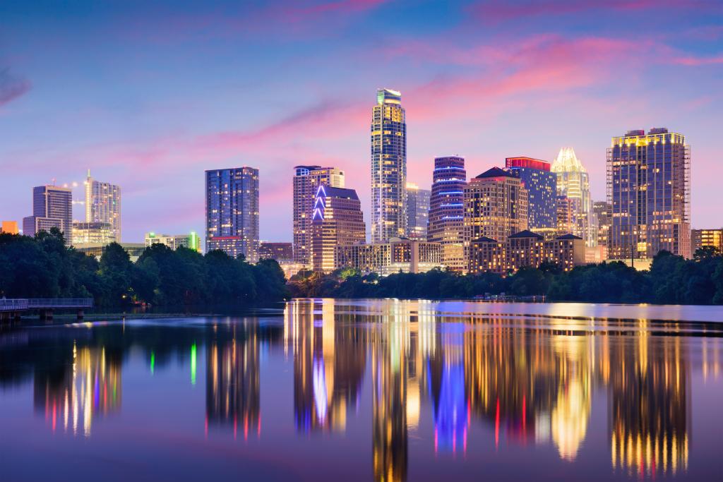 An image of the Austin skyline at sunset with the buildings reflecting onto water.