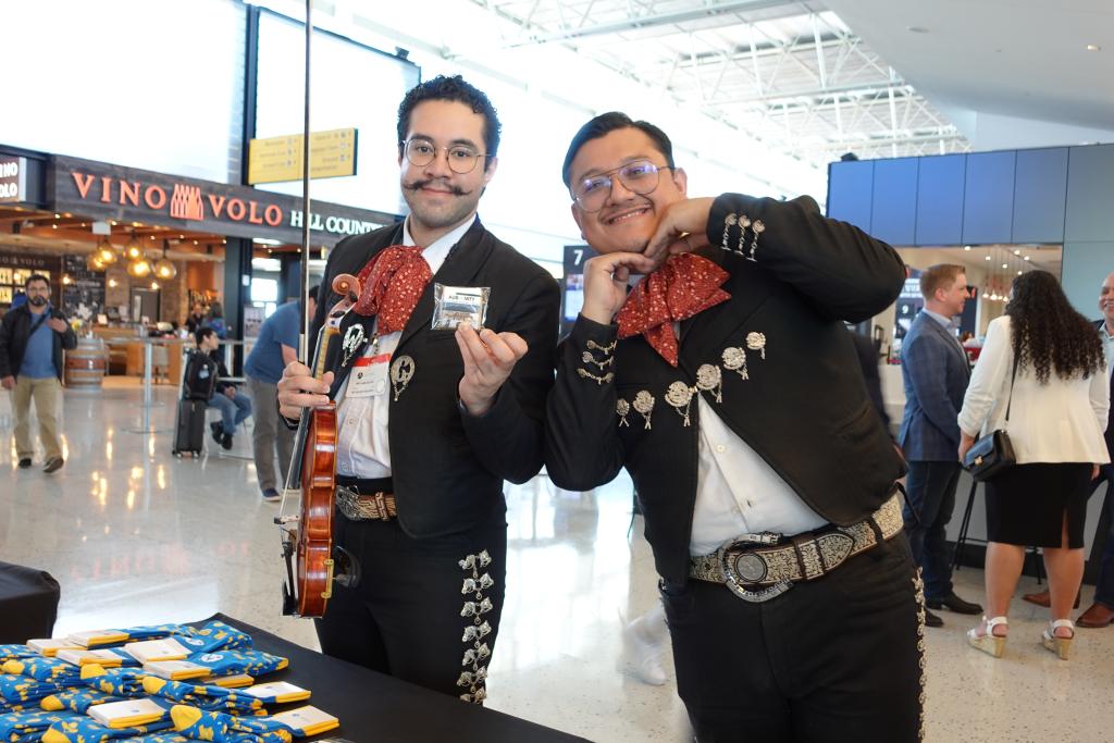 Two members of the mariachi band pose for a photo in the terminal