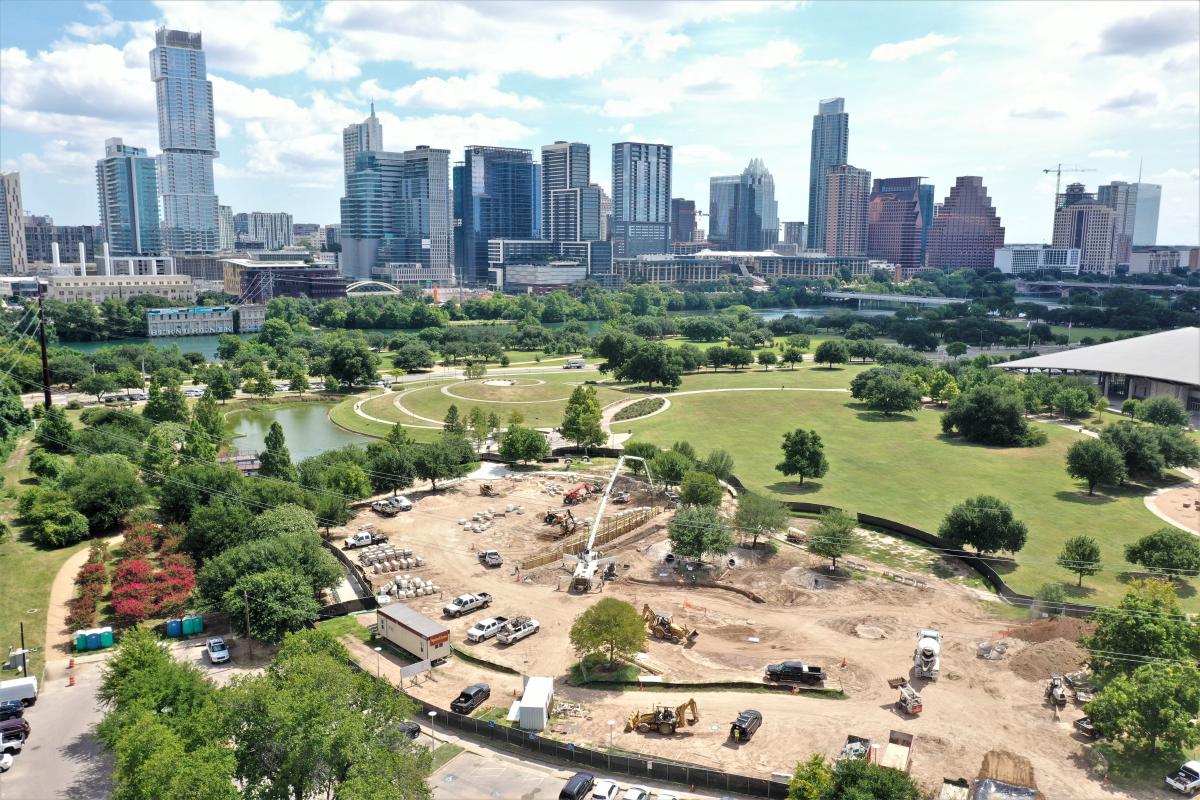 Aerial view of the construction progress with lake and skyline in the background