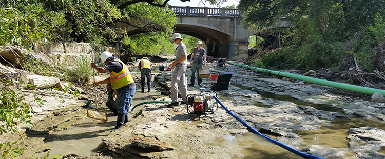Crews lower water levels in Shoal Creek before starting a construction project.
