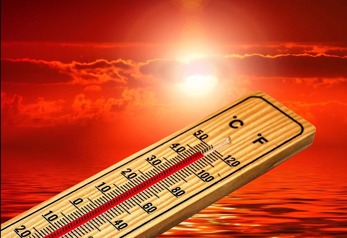 Image of a thermometer showing high temperatures in front of a hot red background with the sun in it