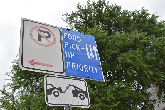 Photo of the recently installed pick-up zone signs that read: "FOOD PICK_UP PRIORITY" with an icon of a fork and knife on the right side of the sign.
