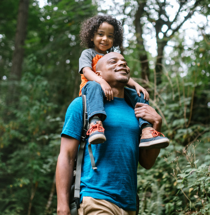 kid riding on shoulders of man