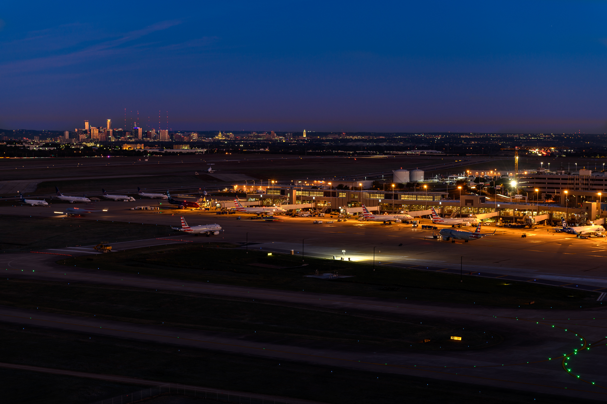 Photo of the Barbara Jordan Terminal at night with downtown Austin skyline in the background.