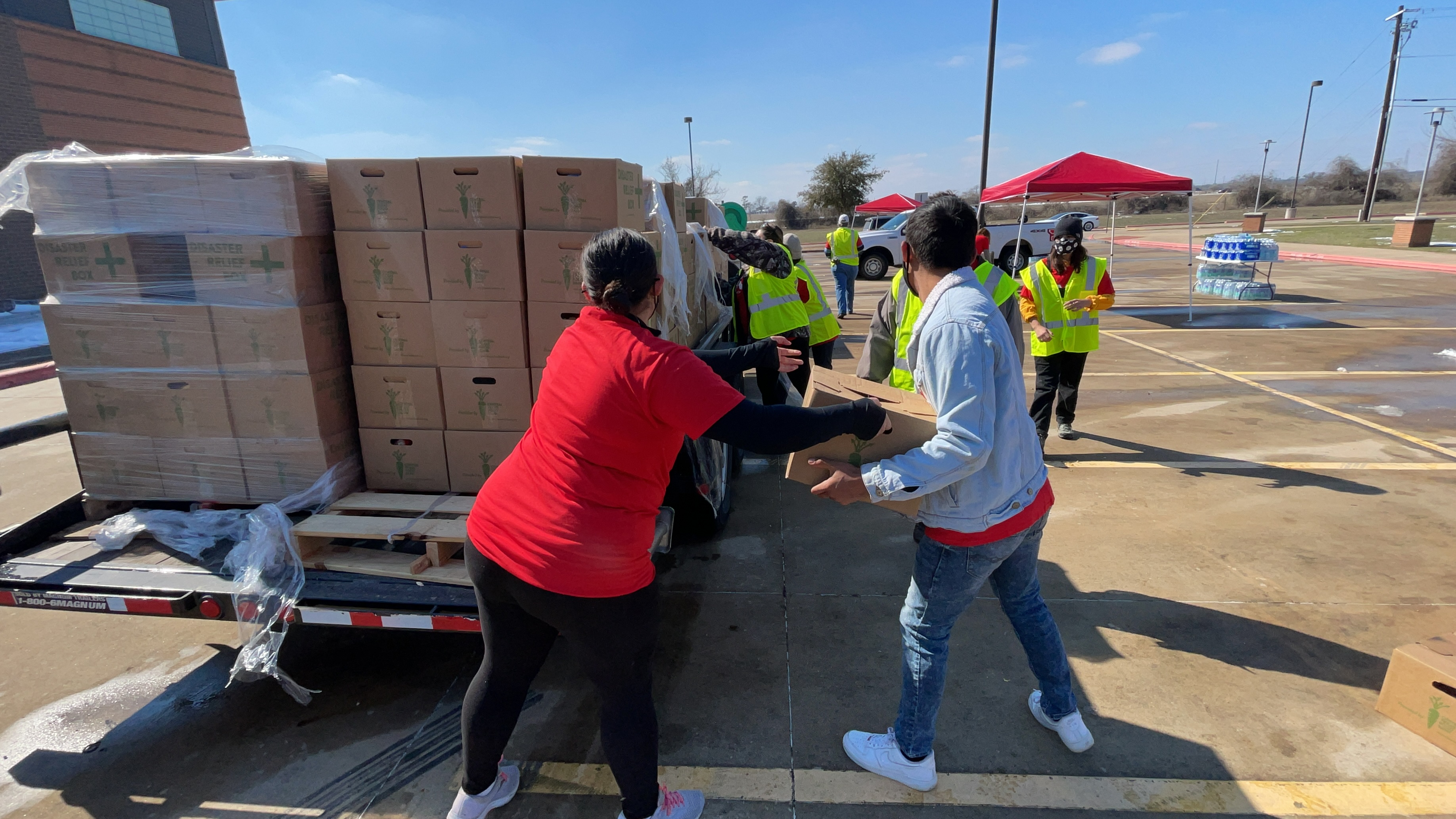 volunteers unload boxes of food from the back of a truck