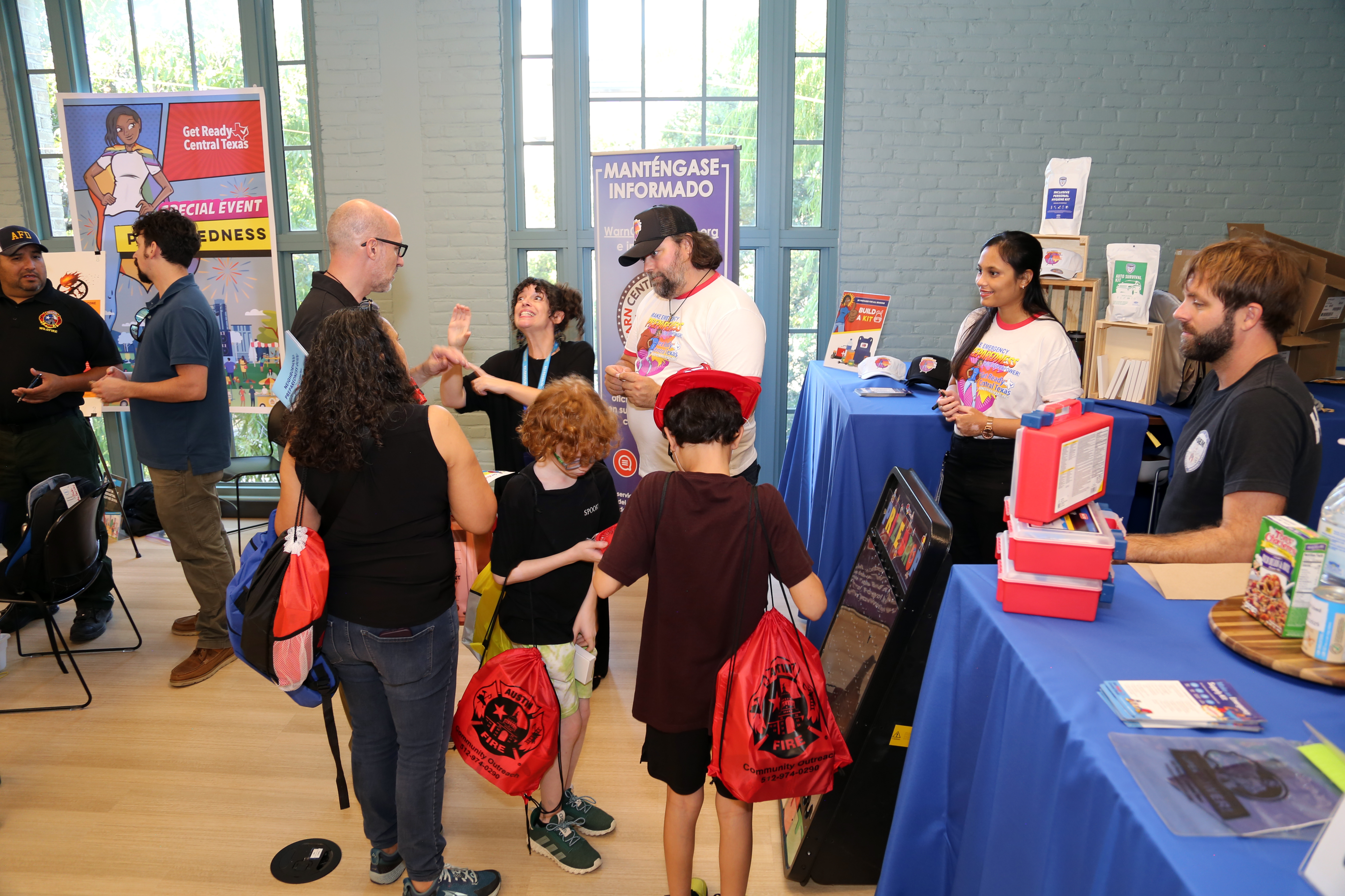 A family receives information about emergency preparedness from city staff at fair booth.