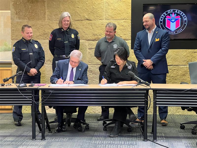 Austin Interim City Manager Jesús Garza and Austin EMS Association President Selena Xie signing contract.