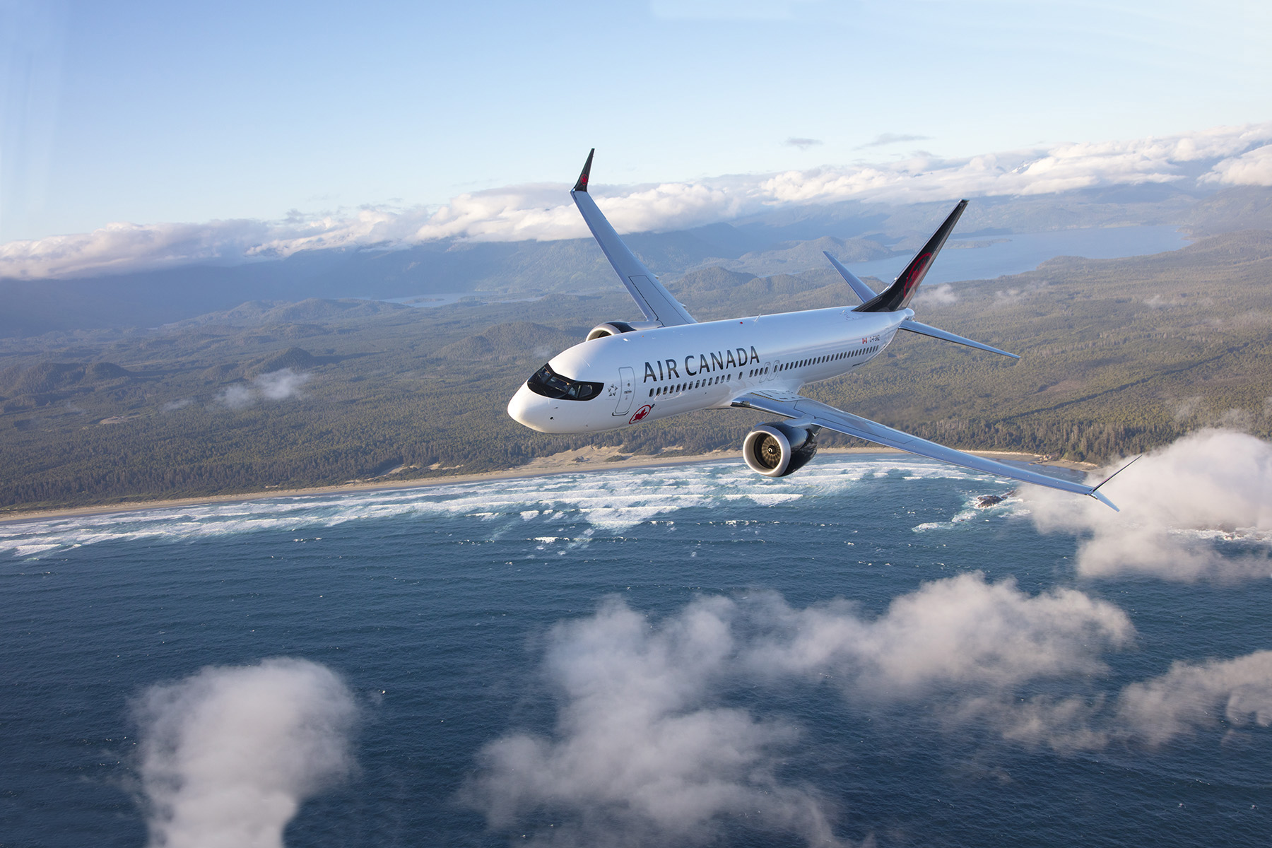 An Air Canada aircraft flies above the clouds and ocean