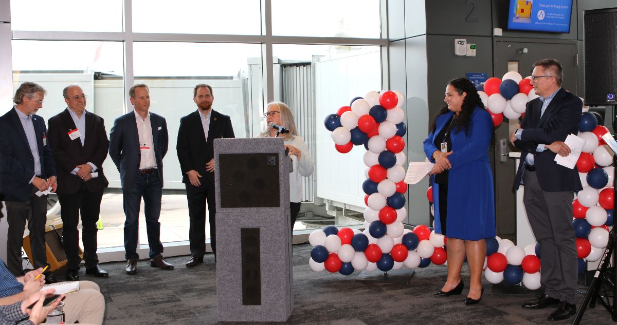 Mayor Pro Tem Leslie Pool at the podium with opening remarks. Speakers next to her, left to right, are Tim Fennell with Travel Texas, Steve Genevosi with Visit Austin, Ed Latson with Opportunity Austin, Jeremy Martin with Austin Chamber of Commerce, Ghizlane Badawi, Interim AUS CEO, and Hubert Frach with British Airways. 