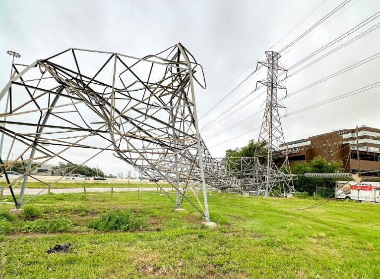 Steel tower that lays twisted and broken on the ground.