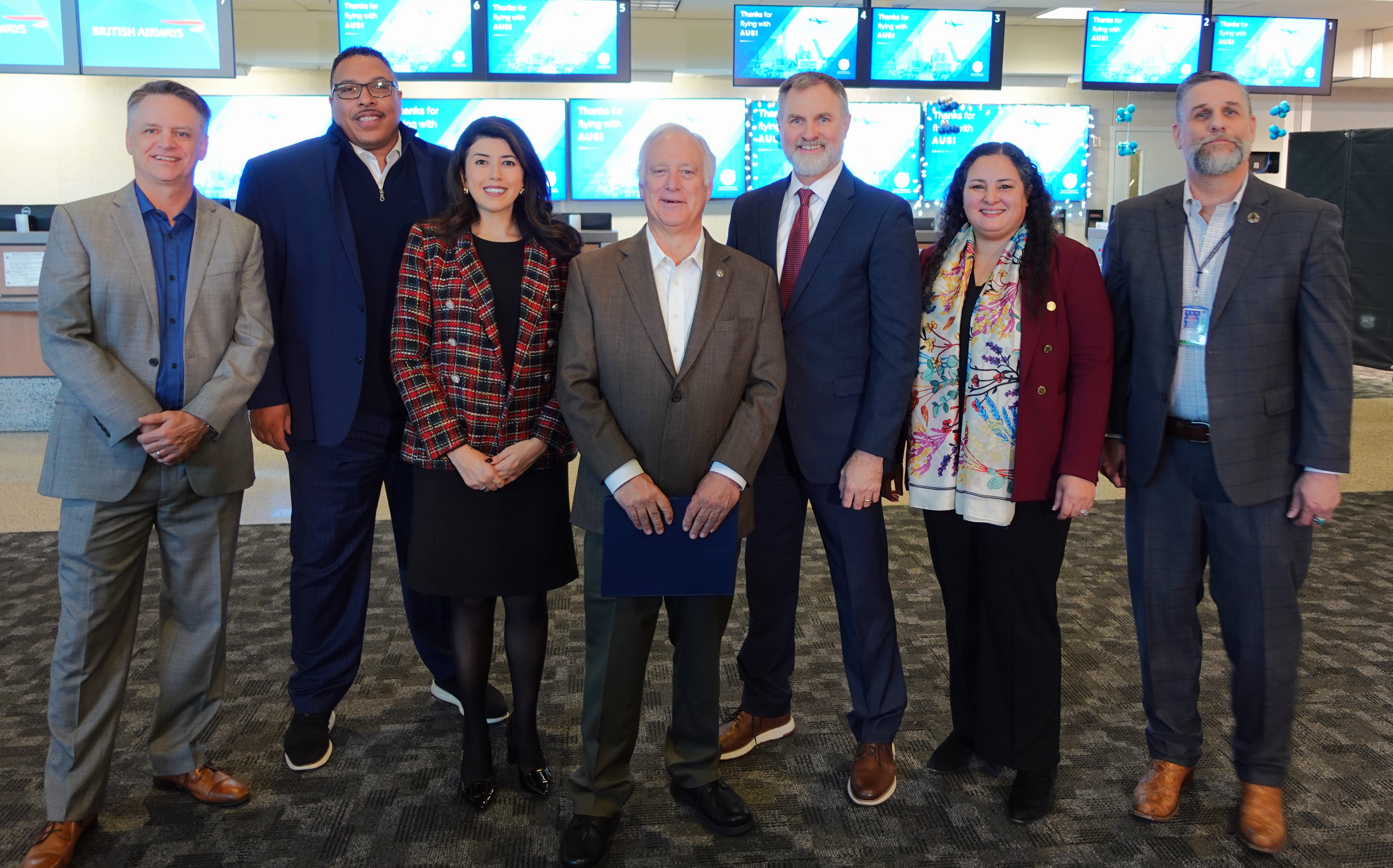 AUS Leadership, TSA and construction partners posing in front of a ticket counter.