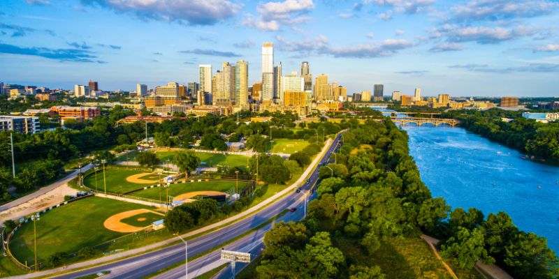 Austin cityscape with blue river in right side of image and skyscrapers in back and green park to left