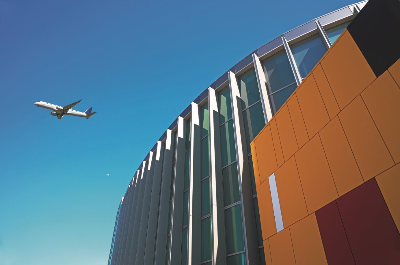 A plane flies above the Barbara Jordan Terminal