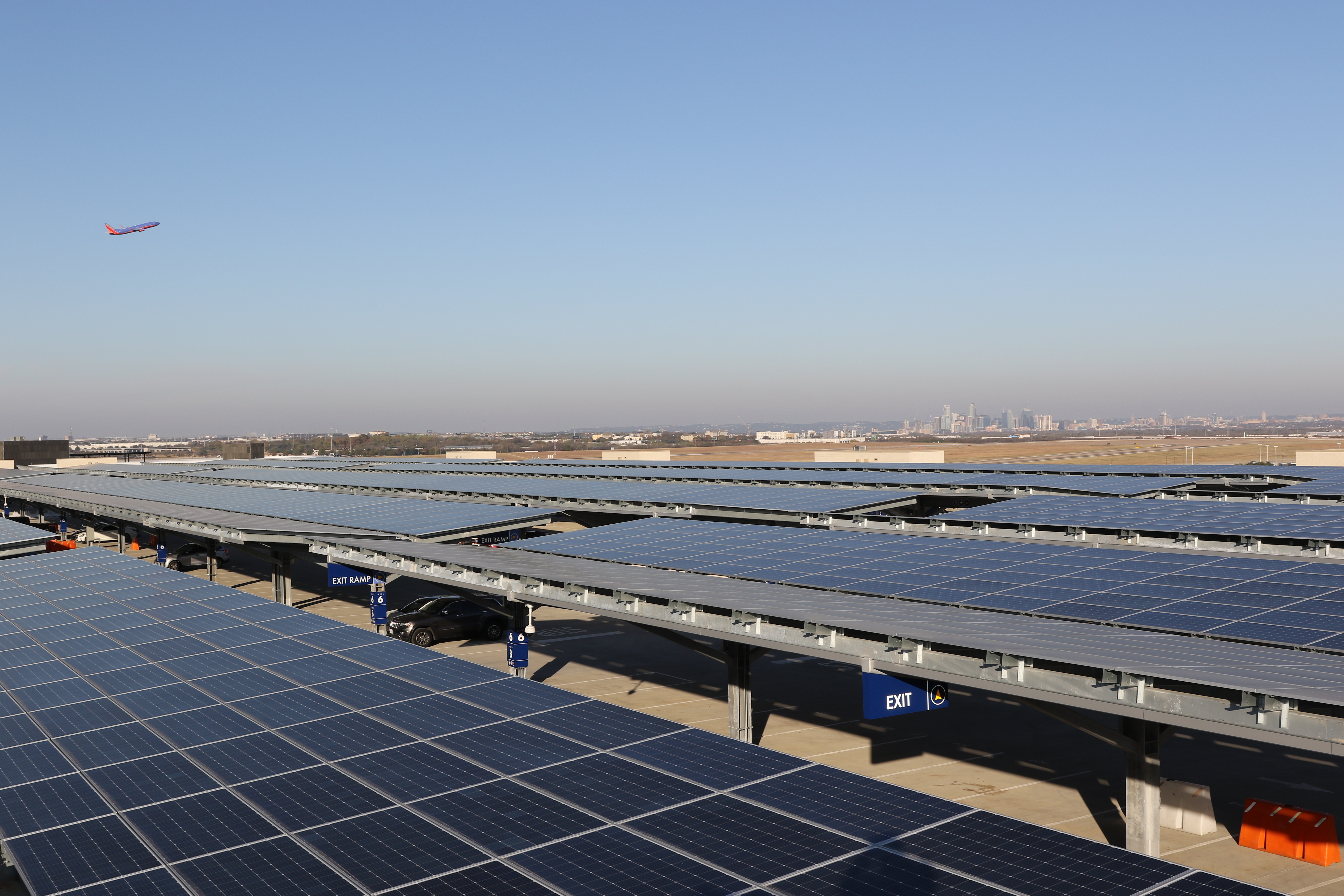 an aircraft flies above the solar panel array at AUS