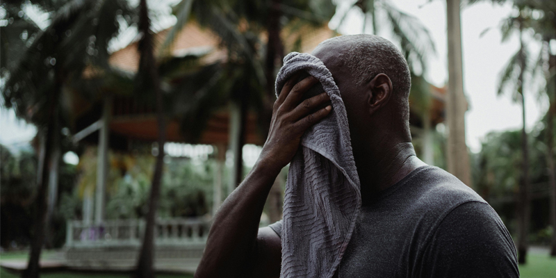 heat general Image of man wiping his face with a towel outside on a hot, sunny day