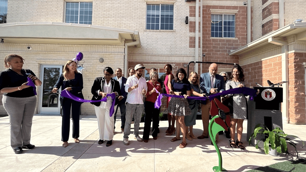 City leadership and community partners cut a ribbon in front of the city's new domestic violence shelter.