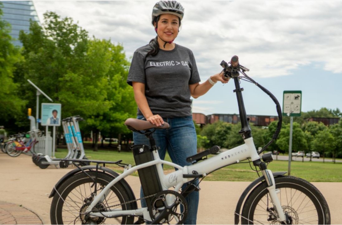 Female standing in front of an E-bike wearing a safety helmet