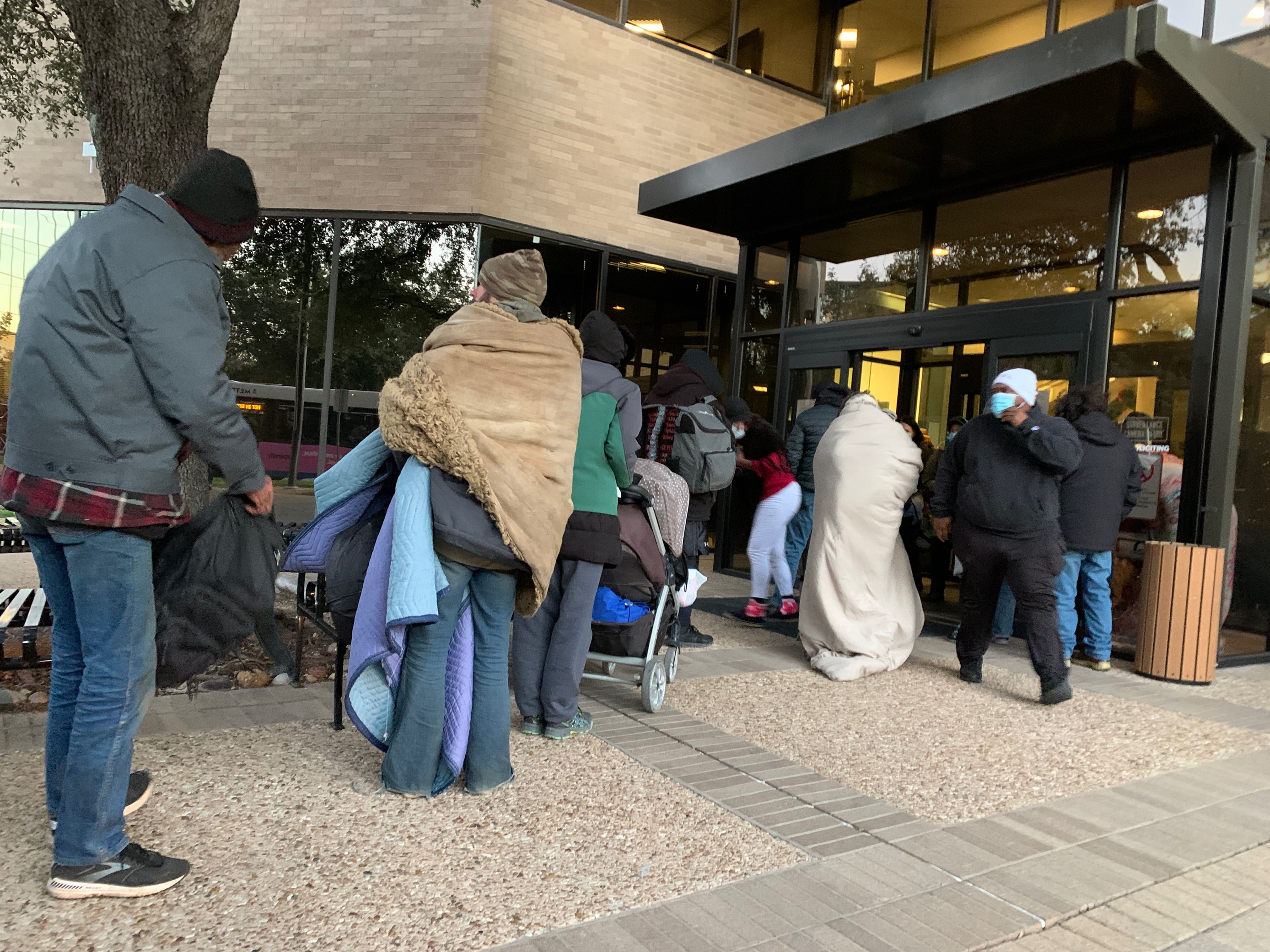 A line of people wait to register for transportation to a Cold Weather Shelter.
