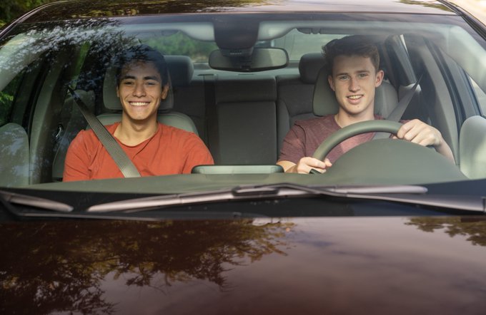 Image of red car with two teens inside