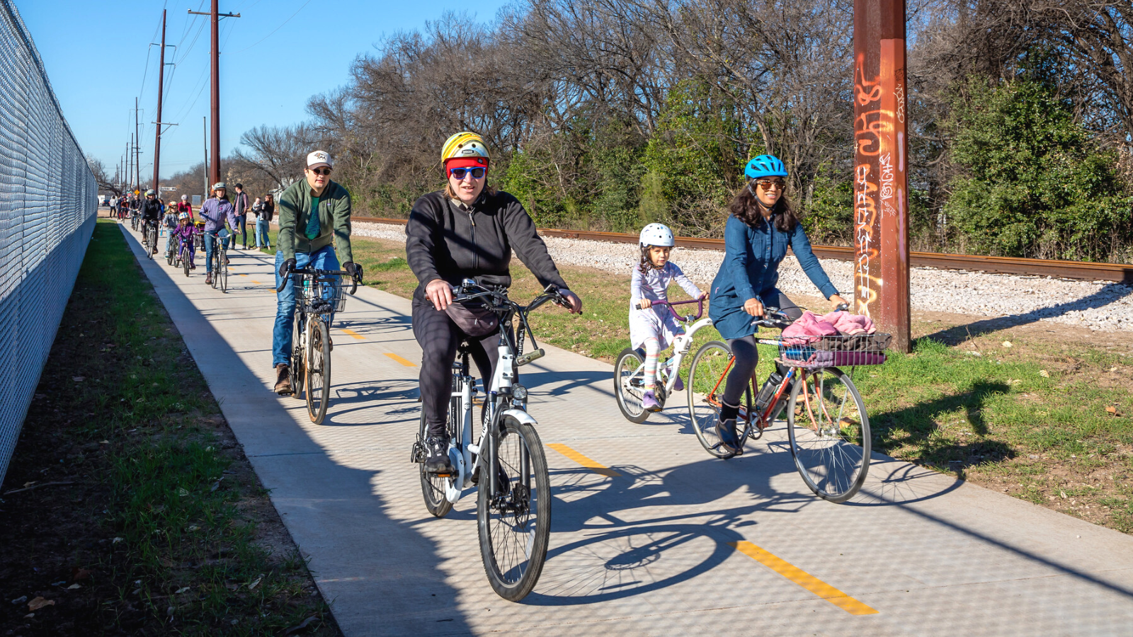 photo of people bicycling on a trail next to a railroad track