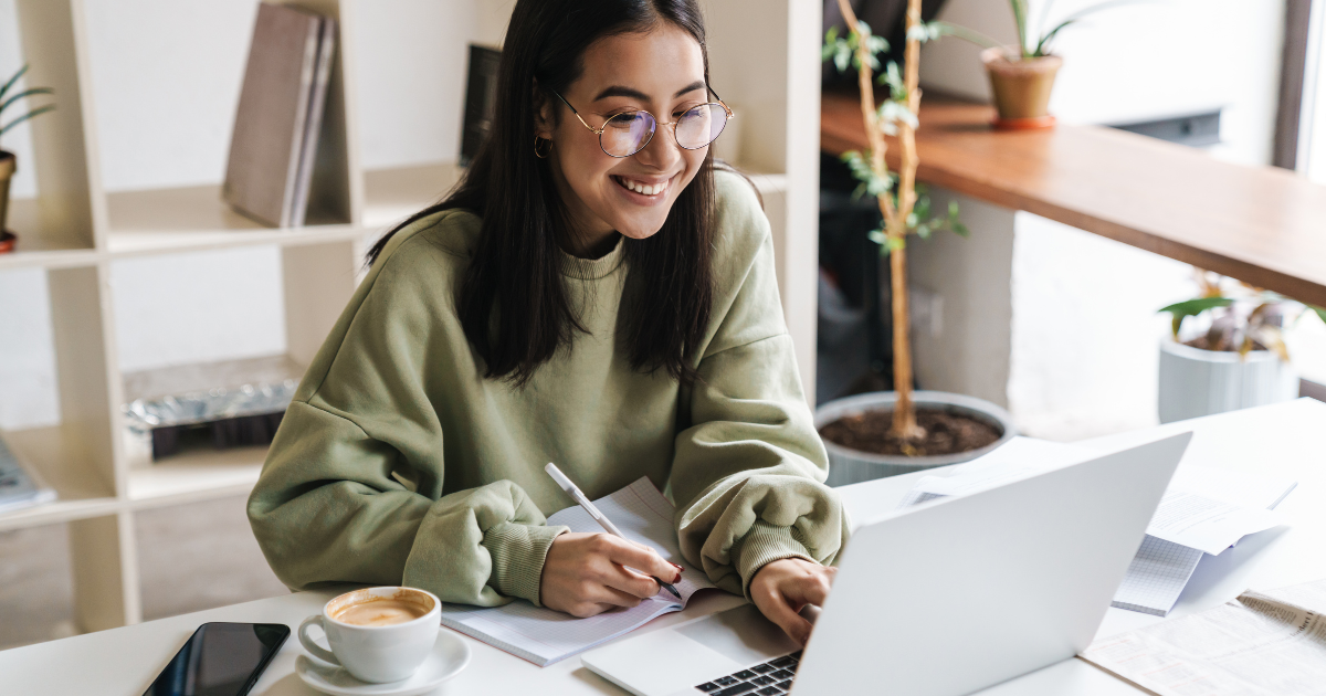 Small Business Training Classes Smiling person working on a laptop with notes and coffee beside them