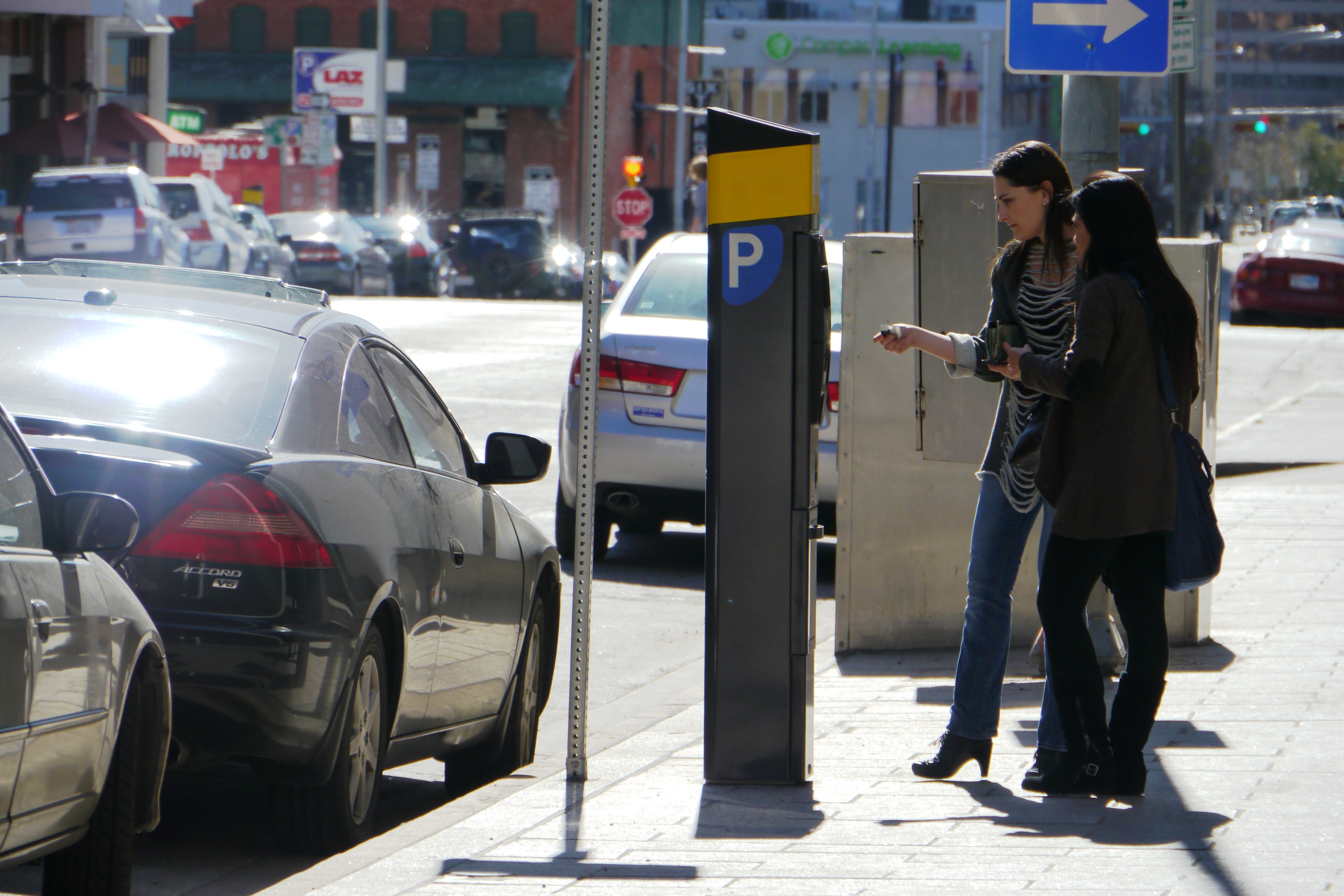 An adult paying for an on-street parking space at a parking kiosk