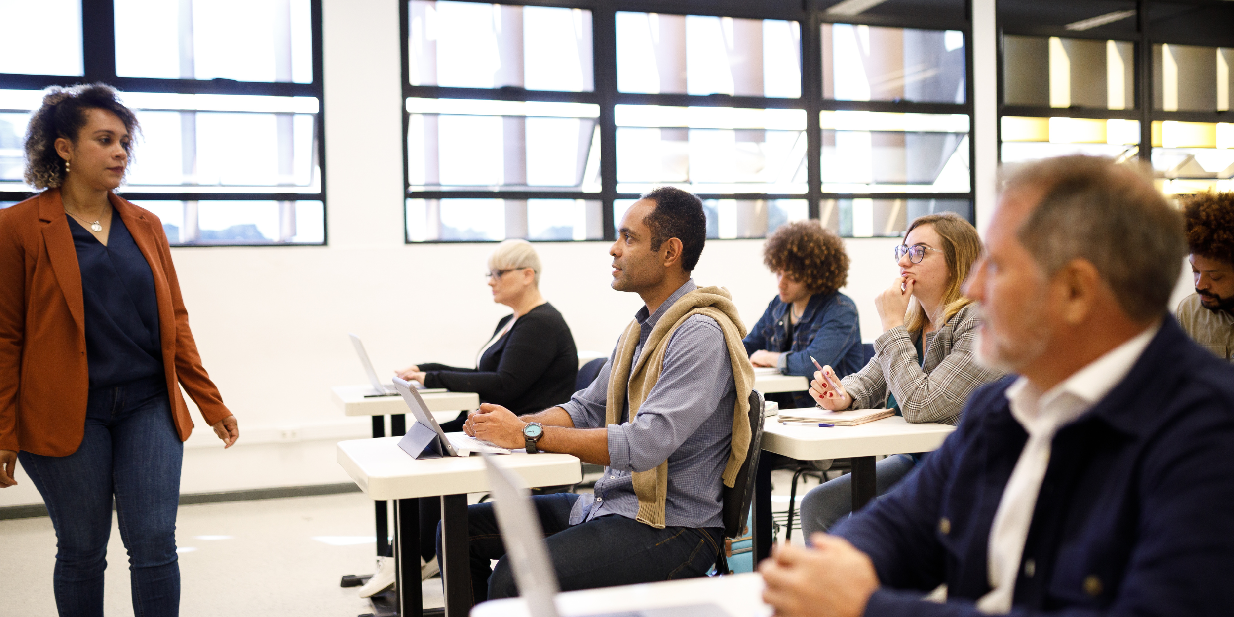 photograph of a woman standing at the head of a classroom, instructing adults