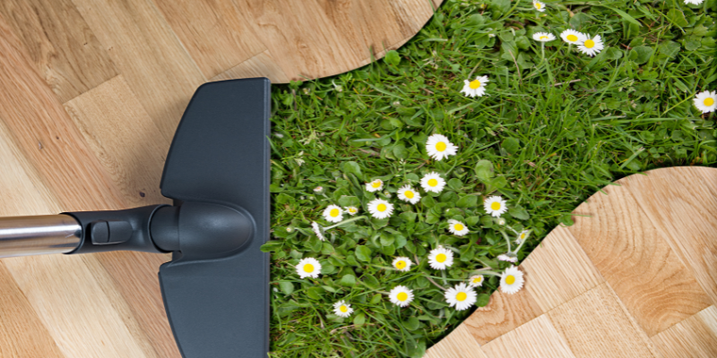 broom sweeping wooden floor to uncover grass and flowers