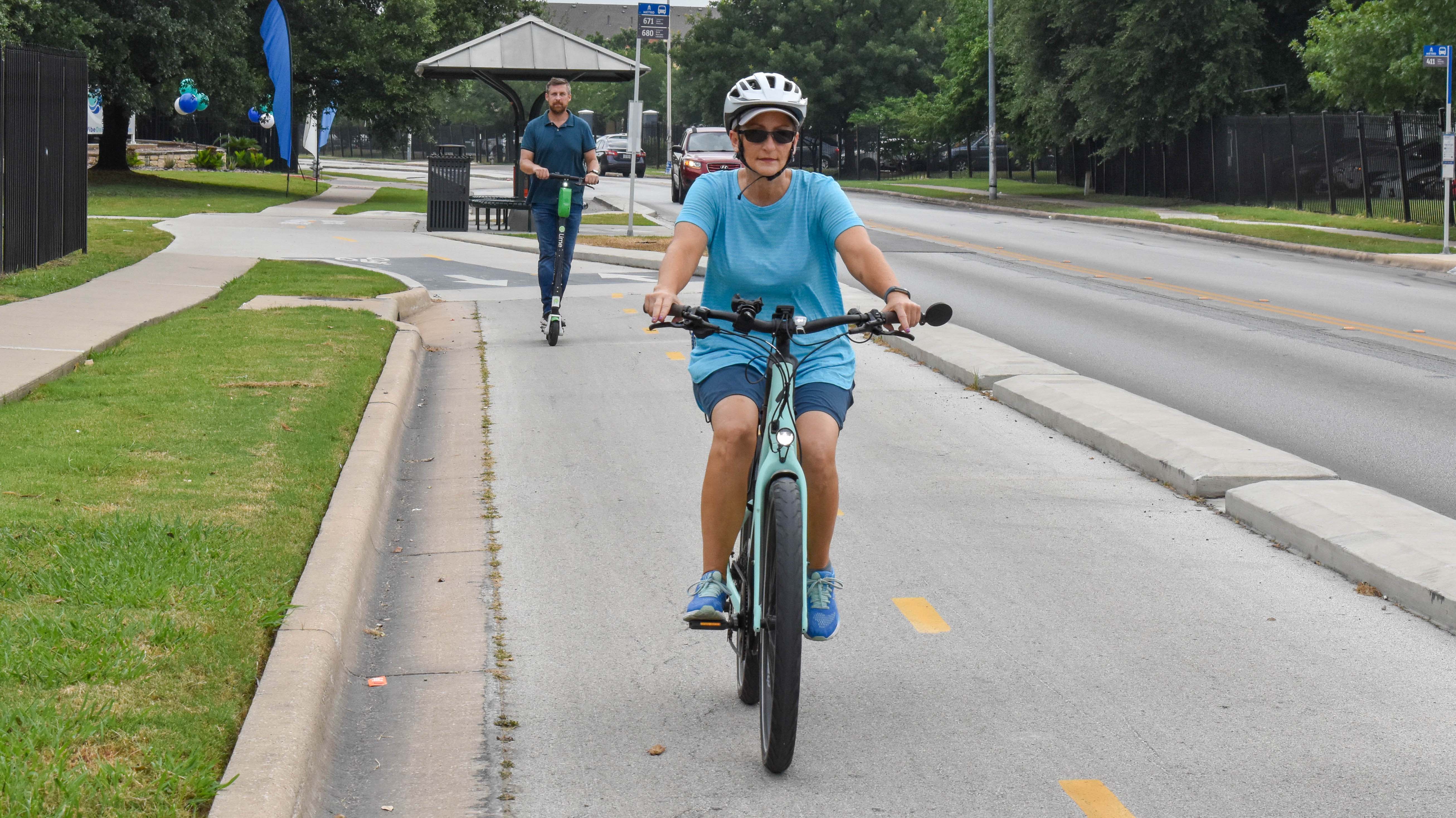 All Ages and Abilities Bicycle Network A bicyclist and scooter user utilize a protected lane on Wickersham Lane in southeast Austin.