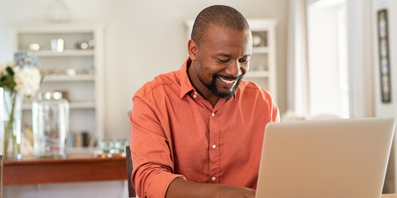 Man smiling while typing on a laptop Man smiling while typing on a laptop
