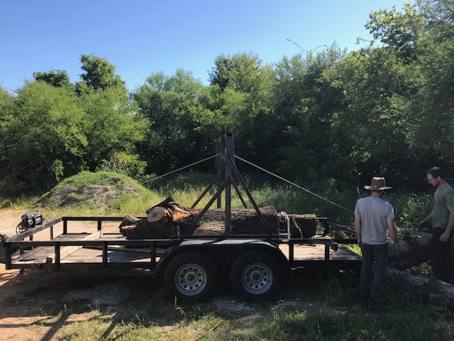 Wood reclamation participants loading a log onto a trailer.