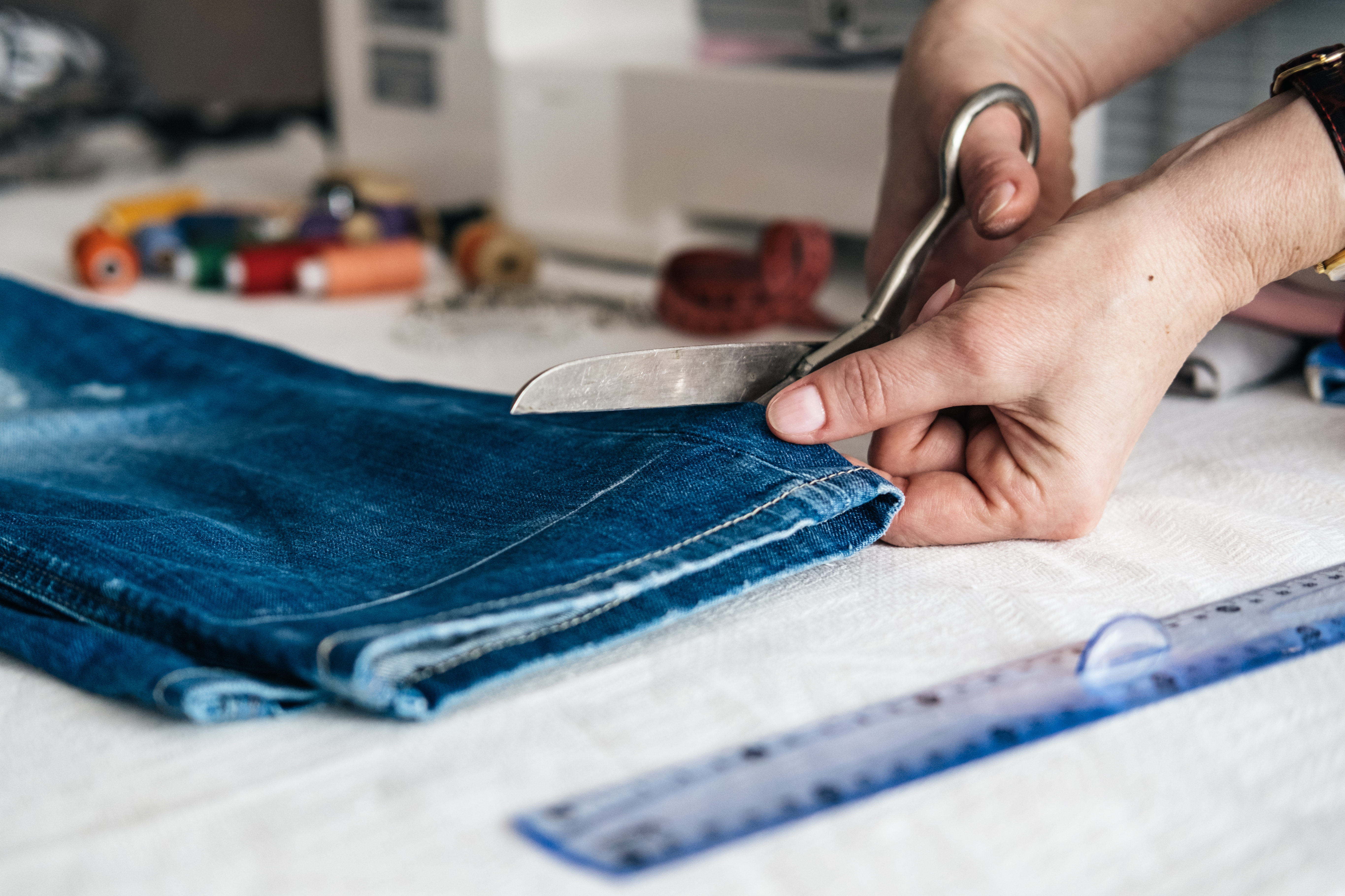 Hemming jeans A person cuts a pair of jeans to be hemmed